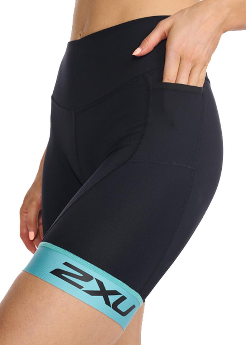 Closeup side view of woman with hand in the right pocket wearing 2XU Women's Core 7 Inch Tri Short - Black/ Porcelain
